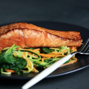 Lachs mit Salat auf schwarzem Teller