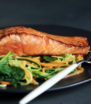 Lachs mit Salat auf schwarzem Teller