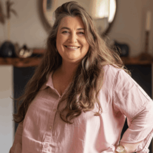 Eine selbstbewusste, lachende Frau in einer pinken Bluse.