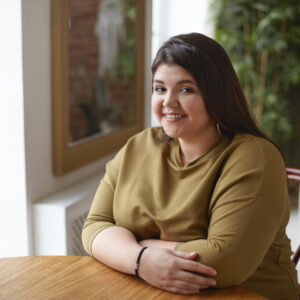 junge plus size Frau sitzt an einem Tisch