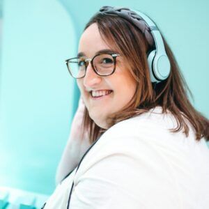 Adipositöse Frau sitzt mit Headset am Schreibtisch und arbeitet.