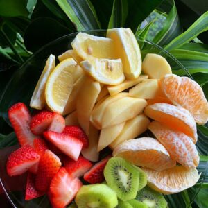 Eine Schüssel mit geschnittenen Stückchen Kiwi, Erdbeeren, Orange, Apfel und Madarinen.