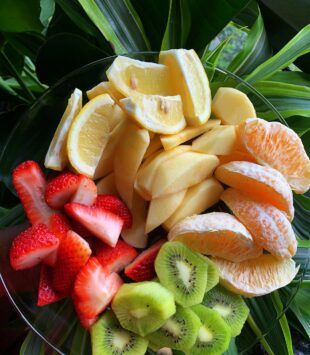 Eine Schüssel mit geschnittenen Stückchen Kiwi, Erdbeeren, Orange, Apfel und Madarinen.