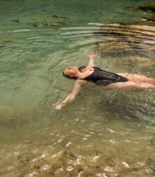 Frau liegt im Wasser und ist glücklich und zufrieden