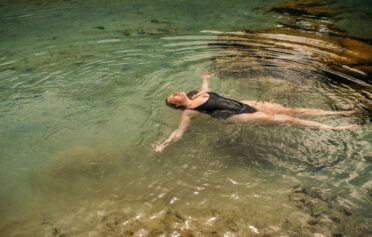 Frau liegt im Wasser und ist glücklich und zufrieden