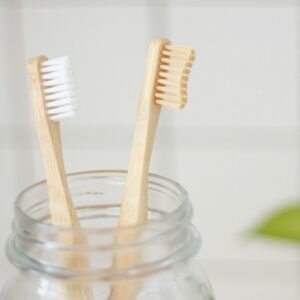 Zwei Zahnbürsten stehen in einem Glas in einem Badezimmer.