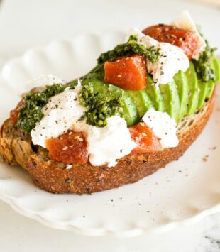 Eine Scheibe Brot belegt mit Avocado, Feta und Melone.