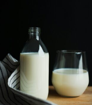 Eine Glasflasche und ein Glas befüllt mit Milch.