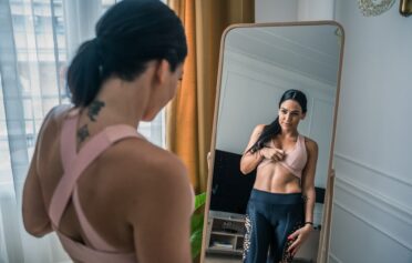 Frau schaut ihren Bauch im Spiegel an