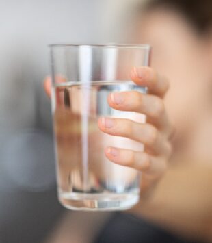 Person hält ein Glas Wasser in der Hand.