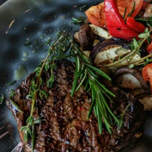 Eine Pfanne mit einem Kräutersteak und Gemüse.