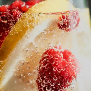 Eine Nahaufnahme von Himbeeren und Zitronen im Wasser.