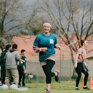 Frau joggt über eine grüne Wiese und wirkt glücklich.