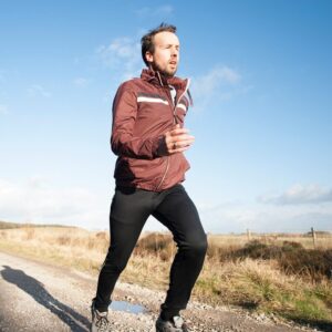 Ein Jogger joggt in der Natur auf einem Schotterweg.