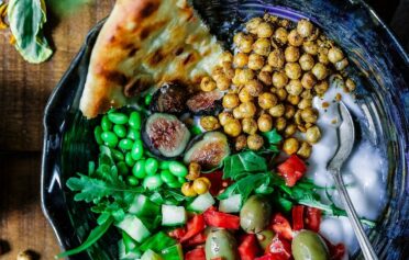 Eine leckere mediterrane Bowl mit Fladenbrot, Kiechererbsen, Edamame, Tomaten und Joghurt.