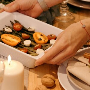 Eine Auflaufform mit frischen Ofengemüse wird auf dem Esstisch gestellt.