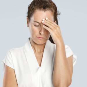 Eine getresste Frau fässt sich an Stirn