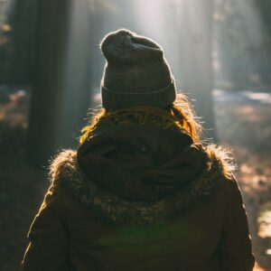Eine Frau mit Mütze im Wald von hinten zu sehen