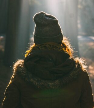 Eine Frau mit Mütze im Wald von hinten zu sehen
