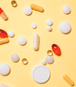 Auf einem gelber Untergrund liegen Tabletten.
