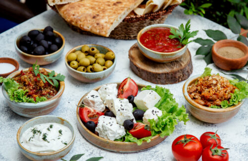 Auf einer Tischplatte stehen verschiedene Schüsseln mit Antipasti Snacks