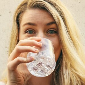 Frau mit langen blonden Haaren trinkt Wasser