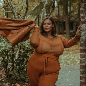 Eine selbstbewuste Plus size Frau in einem Park in orangenem Outfit