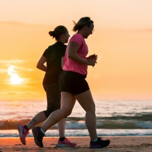 Frauen joggen am Strand bei Sonnenuntergang