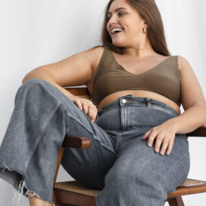 Frau mit Jeans auf einem Stuhl vor weißen Hintergrund