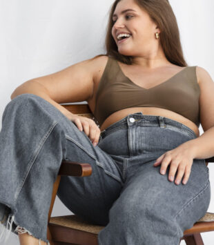 Frau mit Jeans auf einem Stuhl vor weißen Hintergrund