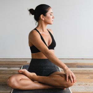 Frau macht Yoga auf einer Matte und dreht sich gerade nach hinten mit dem Oberkörper