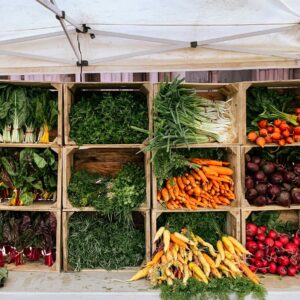 Holzkisten übereinander als eine Art Regal gestapelt, darin befinden sich verschiedene Gemüsesorten.