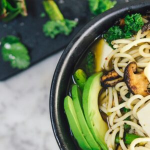 Bowl mit grünem Gemüse und Reisnudeln auf einer Mamorplatte