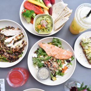 verschiedene Teller mit proteinreichen Gerichten, wie Lachs, Gemüse, Huhn, Brot