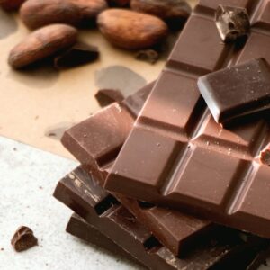 drei Tafel Schokolade gestapelt, daneben liegen Kakao Bohnen