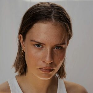 Frau mit Schulterlange Haaren schaut fokussiert und stark in die Kamera.