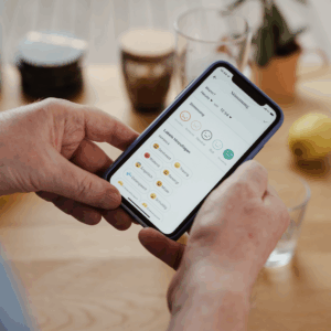 zwei Hände halten ein Handy, auf welchem die Oviva App geöffnet ist