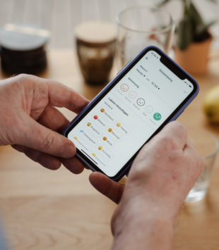 zwei Hände halten ein Handy, auf welchem die Oviva App geöffnet ist