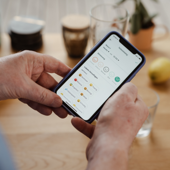 zwei Hände halten ein Handy, auf welchem die Oviva App geöffnet ist