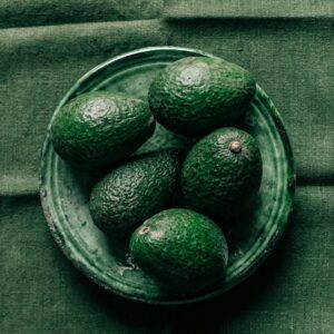 Avocados auf einem grünen Teller auf einer grpnen Decke.