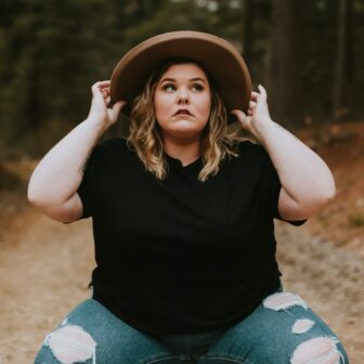 Plus size Frau im Wald guckt nach oben.