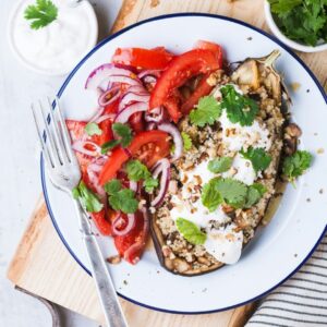 Befüllte Aubergine mit Gemüse und einem Tomatensalat als Beilage.