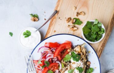 Befüllte Aubergine mit Gemüse und einem Tomatensalat als Beilage.