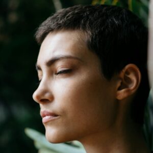 Frau steht in der Natur und atmet tief durch