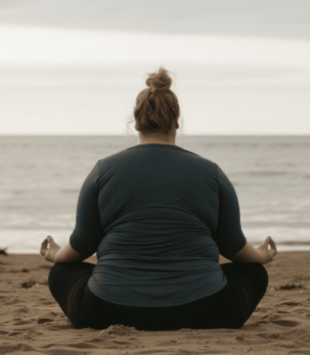 PLus size Frau meditiert am Strand.