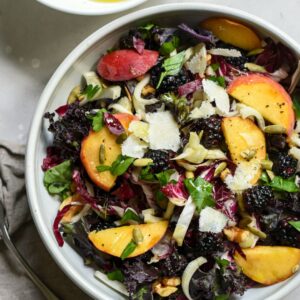 Schale mit buntem Salat und Dressing in einer Schüssel daneben.