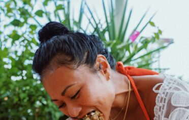 Eine asiatische Frau isst einen Burrito und sieht sehr glücklich dabei aus.