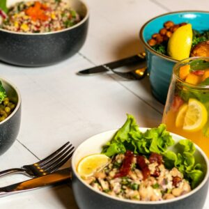 Verschiedene Bowls mit Gemüse stehen auf einem gedeckten Tisch.