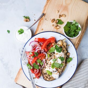 Aubergine mit Tomatensalat auf einem weißen Teller garniert.