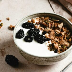 Eine Schüssel mit Joghurt, Brombeeren und Granola.